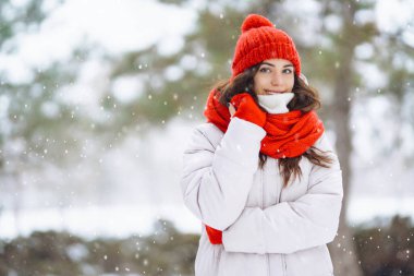 Güzel bir kadın karlı ağaçların arasında duruyor ve ilk karın tadını çıkarıyor. Kış tatilin kutlu olsun. Noel.