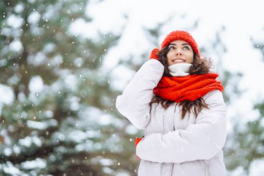 Güzel bir kadın karlı ağaçların arasında duruyor ve ilk karın tadını çıkarıyor. Kış tatilin kutlu olsun. Noel.