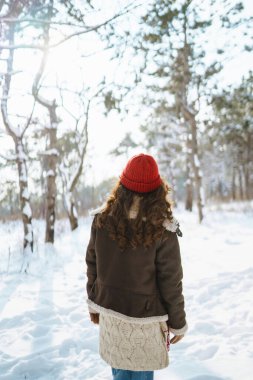 Mutlu kadın karlı ağaçların arasında duruyor ve ilk karın tadını çıkarıyor. Tatiller, dinlenme, seyahat konsepti