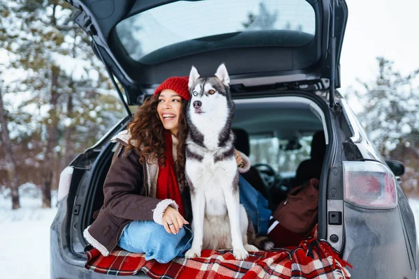 年轻女人和可爱的哈士奇狗在外面享受着进入车里的乐趣 旅行概念 — 图库照片
