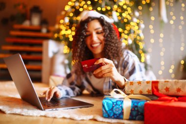 Kredi kartı, hediyeler ve dizüstü bilgisayarı olan genç bir kadın. Noel tatilinde online alışveriş. 