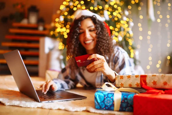 Young woman with credit card, gifts, and laptop. Online shopping at Christmas holidays.