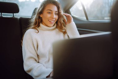 Arabada otururken dizüstü bilgisayarda çalışan güzel ve kendinden emin bir kadın. İş konsepti. 