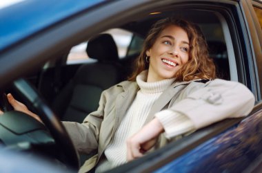 Şehirde araba süren genç bir kadın. Araba paylaşımı, kiralama servisi veya taksi uygulaması.