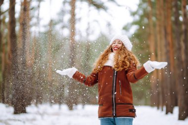Kış gülen kadın kış ormanlarında karlı ağaçların arasında duruyor..