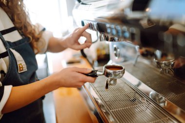 Barista elinde kahve bardağıyla kahve makinesinin hazırladığı taze kahveyi getiriyor. Profesyonel kahve demleme..