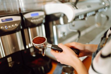 Barista elinde kahve bardağıyla kahve makinesinin hazırladığı taze kahveyi getiriyor. Profesyonel kahve demleme..