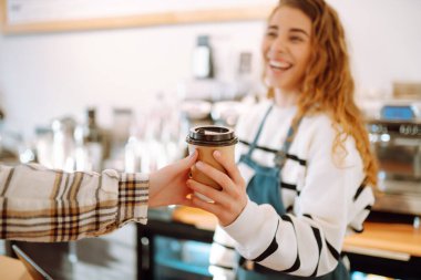 Gülümseyen barmen kız müşterilere kahve fincanı veriyor..  