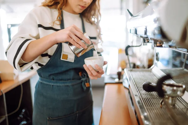 Barista elinde kahve bardağıyla kahve makinesinin hazırladığı taze kahveyi getiriyor. Profesyonel kahve demleme..