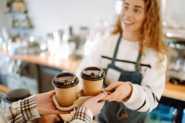 stock image Smiling barista- girl giving take away coffee cups to a customers.  