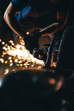 Öğütücüyle ustanın elleri. Metal atölyede çalışıyor. Metal işçiliğinde kıvılcımlar.