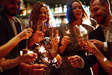 Arkadaşların elinde parlayan maytaplar. Partide maytap tutan bir grup insan. Kış tatili, tatil, rahatlama ve yaşam tarzı konsepti.