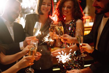 Arkadaşların elinde parlayan maytaplar. Partide maytap tutan bir grup insan. Kış tatili, tatil, rahatlama ve yaşam tarzı konsepti.