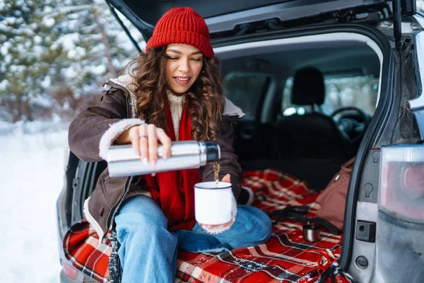 Jonge Vrouw Houdt Een Thermoskan Drinkt Thee Zittend Kofferbak Winter — Stockfoto
