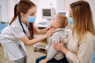 Çocuk doktoru hasta çocuğu muayene ediyor. Annesiyle birlikte bir çocuk, çocuk doktoru ya da otolaringolojistin ofisinde..
