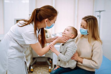 Çocuk doktoru hasta çocuğu muayene ediyor. Annesiyle birlikte bir çocuk, çocuk doktoru ya da otolaringolojistin ofisinde..