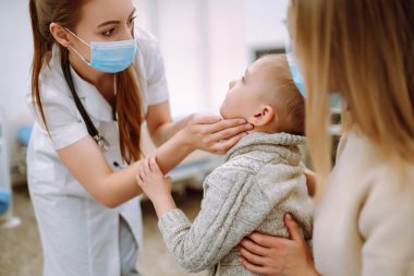 Çocuk doktoru hasta çocuğu muayene ediyor. Annesiyle birlikte bir çocuk, çocuk doktoru ya da otolaringolojistin ofisinde..