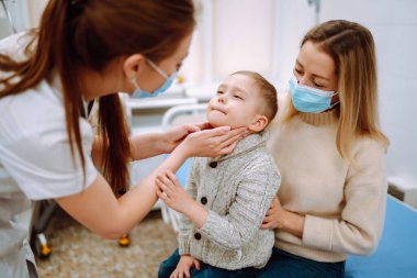 Çocuk doktoru hasta çocuğu muayene ediyor. Annesiyle birlikte bir çocuk, çocuk doktoru ya da otolaringolojistin ofisinde..