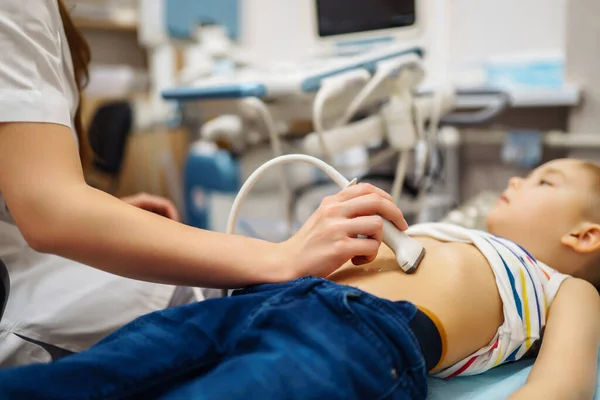 診療所で超音波検査を受けてる少年 小児用腹腔鏡ソノグラムを作る医師 — ストック写真