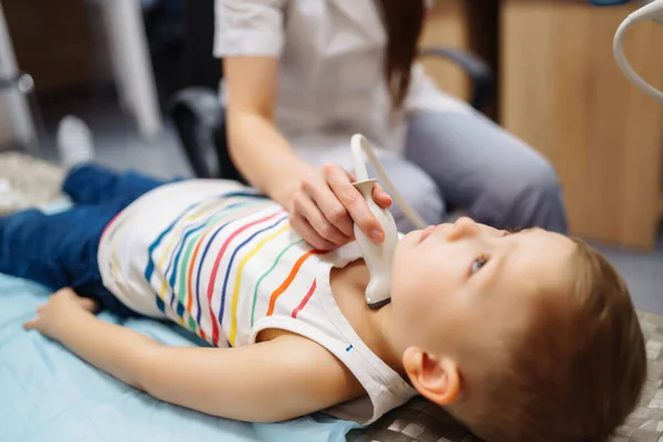 甲状腺超音波検査を受けている小さな男の子 近代的な装置で診療所で子供の喉を調べる医者 医療の概念 — ストック写真