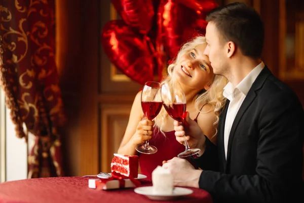 Young couple having a romantic dinner and toasting with glass of red wine. Valentine\'s Day concept. Relationship, surprise and love concept.