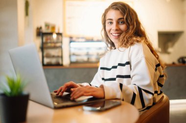 Young woman sits in a cafe and works on a computer. Business, blogging, freelance, education concept.