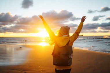 Happy tourist in a yellow jacket enjoying sea landscape at sunset. Travelling, lifestyle, adventure.