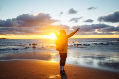 Happy tourist in a yellow jacket enjoying sea landscape at sunset. Travelling, lifestyle, adventure.