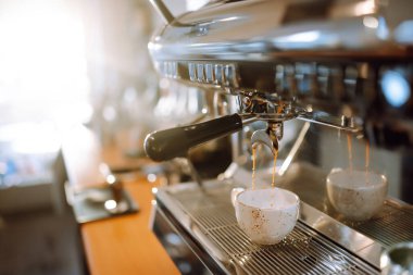 Hot delicious coffee pouring from coffee machine into coffee cup.