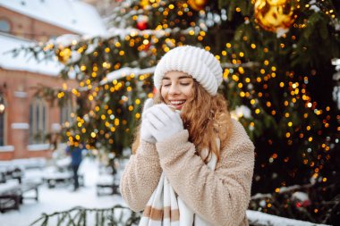 Beautiful woman playing with snow on winter street.  Fashion young woman in the winter park. Christmas.