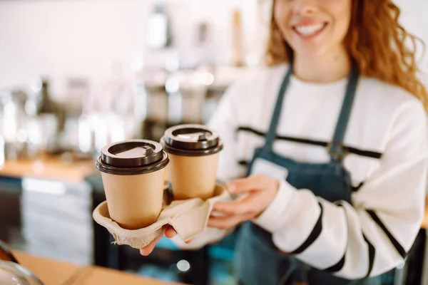 テイクアウトコーヒー バリスタの女の子が喫茶店でコーヒーを飲んでいる 持ち帰り用食品 — ストック写真
