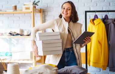 Small business owner, entrepreneur, seller using tablet checking ecommerce clothing store orders. Online sales. Shopping concept.