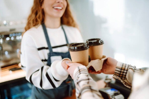 Barista girl holding take away coffee at the cafe shop. Takeaway food.