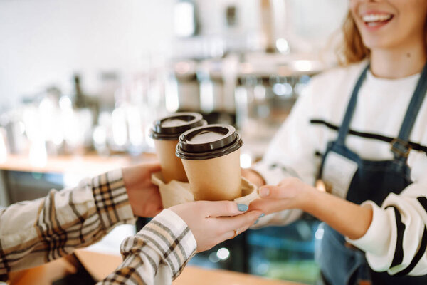 Barista girl holding take away coffee at the cafe shop. Takeaway food.