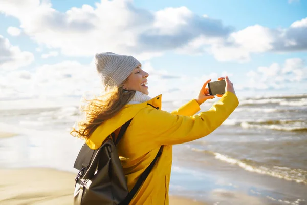 Woman travel blogger takes selfie for social networks  by the sea at sunset. Travel, tourism and blogger concept.