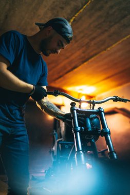 Motorcycle repair. Disassembled motorcycle. The expert works with electric welding of metal. Instruments and equipment.