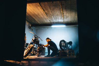 Motorcycle repair. Disassembled motorcycle. The expert works with electric welding of metal. Instruments and equipment.