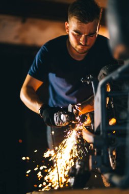 Motorcycle repair. Disassembled motorcycle. The expert works with electric welding of metal. Instruments and equipment.