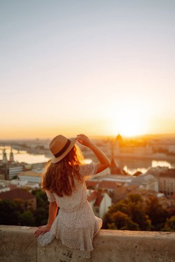 Young female tourist  looking at panoramic view of  the city at sunset. Lifestyle, travel, tourism, nature, active life.