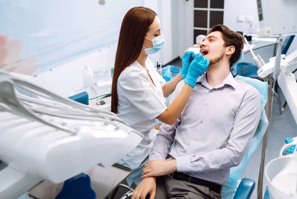 Man at the dentist\'s chair during a dental procedure. Overview of dental caries prevention.  Healthy teeth and medicine concept.