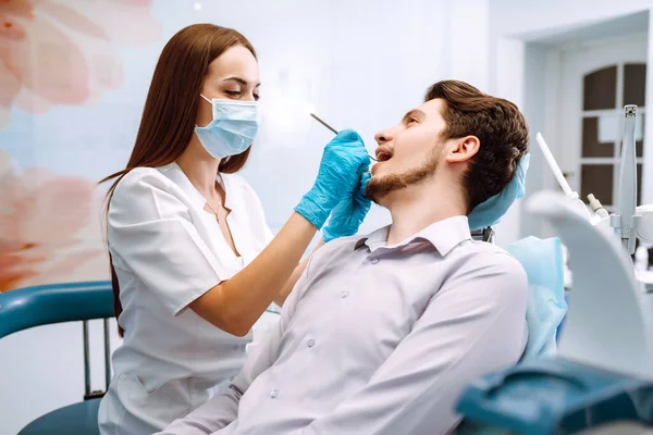 Man at the dentist\'s chair during a dental procedure. Overview of dental caries prevention.  Healthy teeth and medicine concept.