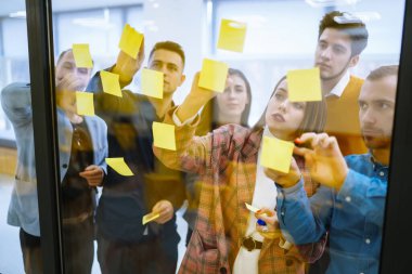 Group of business people collaborating in office discussing and planning strategy Front of glass wall marker and stickers. Education, analysis, planning management concept.