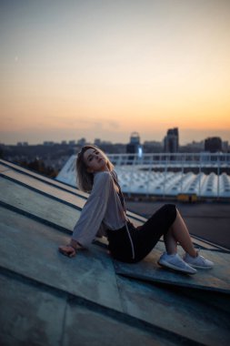 Young woman in the roof enjoying sunset, freedom city atmosphere. People, lifestyle, relaxation concept.