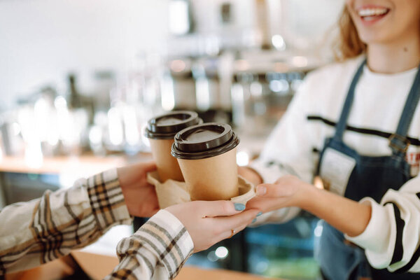Barista woman at coffee shop holding  take away coffee. Takeaway food.