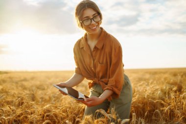Young Female farmer with tablet in the field. Agriculture, gardening, business or ecology concept. Growth dynamics.