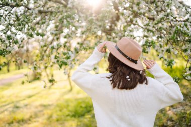 Young beautiful woman relaxing in blooming  garden. Spring,  romantic and lifestyle concept.