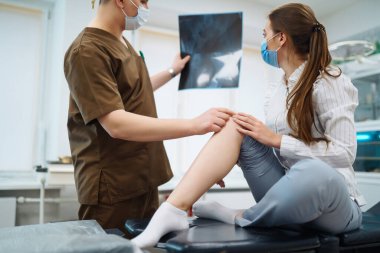 Doktor hastanın bacağının röntgenini inceliyor. Ayak ve burkulma kavramı. Spor sakatlıkları..