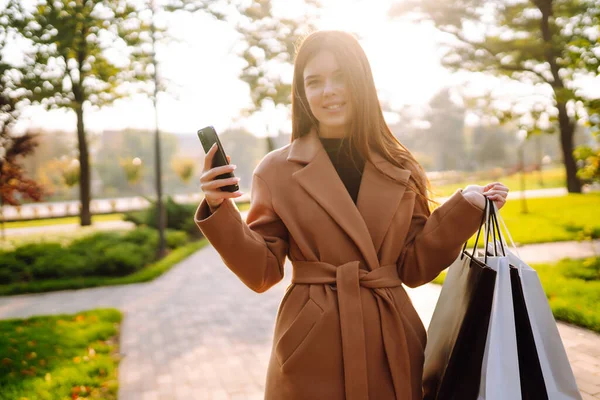 携帯電話で買い物袋を持った笑顔の女性 黒の金曜日 販売の概念 オンラインショッピングのコンセプト — ストック写真