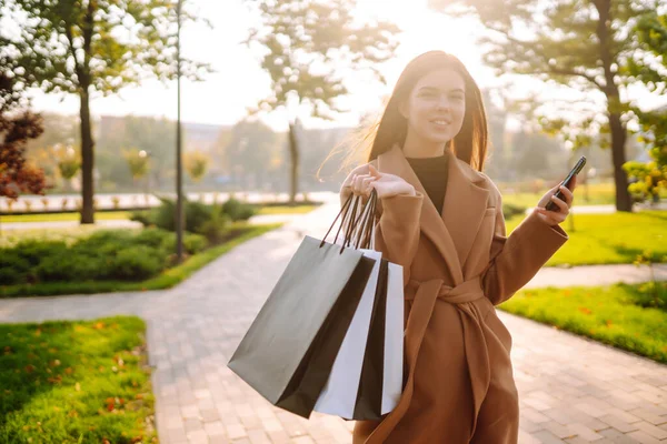 用她的手机用购物袋微笑的女人采购 黑色星期五 销售概念 网上购物概念 — 图库照片