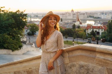 Gün batımında şehir merkezine bakan genç bir bayan turist. Seyahat ve turizm kavramı.